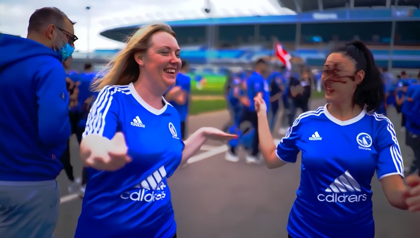 Zwei weibliche Fans des FC Schalke 04 die freudig erregt zu dem Eröffnungsspiel der 2. Fußballbundesliga gehen. Achte darauf, dass die Trikots von Adidas sind und der Sponsor VELTINS ist.