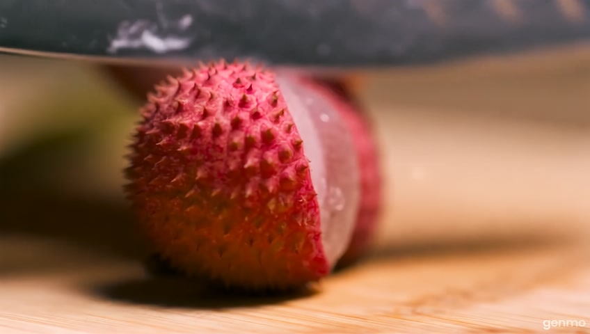 Realistic 4K footage close-up of a knife rapidly cutting a lychee on a wooden cutting board. It slices it multiple times, each slice falls over as the knife moves to the next. The inside of the fruit is also glass. The sound is ASMR style