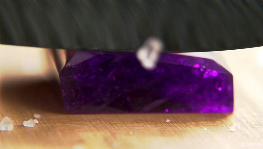 A close-up animation of a carbon fiber knife slowly slicing through a dark purple crystal-like stone on a wooden cutting board. The hand gently applies pressure while the blade glides smoothly and realistically through the faceted surface of the stone. Ice shards and salt particles fall as the blade advances. Subtle reflections and shadows move naturally with the cut. Add slight hand and knife motion for realism