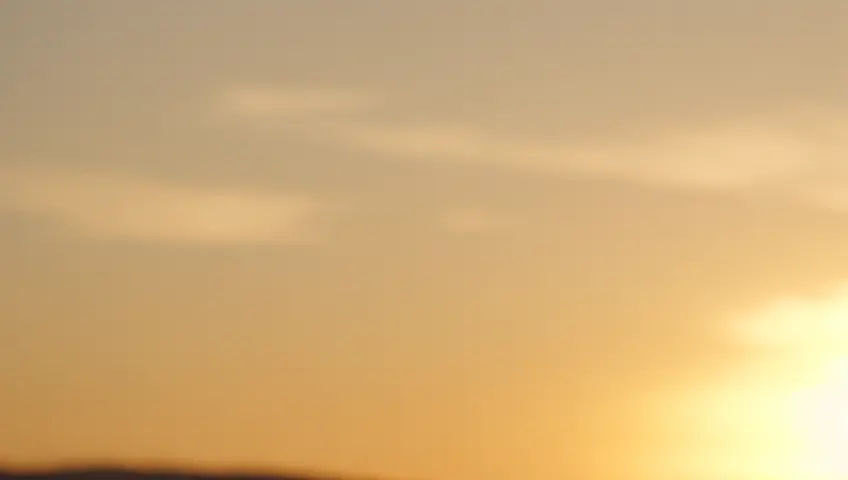 A slow-motion shot of bubbles floating through the air at sunset, reflecting the golden light. The camera captures the iridescent surfaces and serene movement.