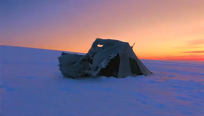 casa de campaña rota en un monte lleno de nieve y es el atardecer