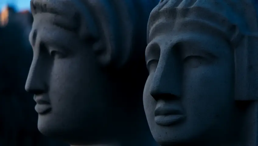 A time-lapse of shadows moving across the faces of ancient stone statues as the sun sets. The camera captures the passage of time and historical significance.