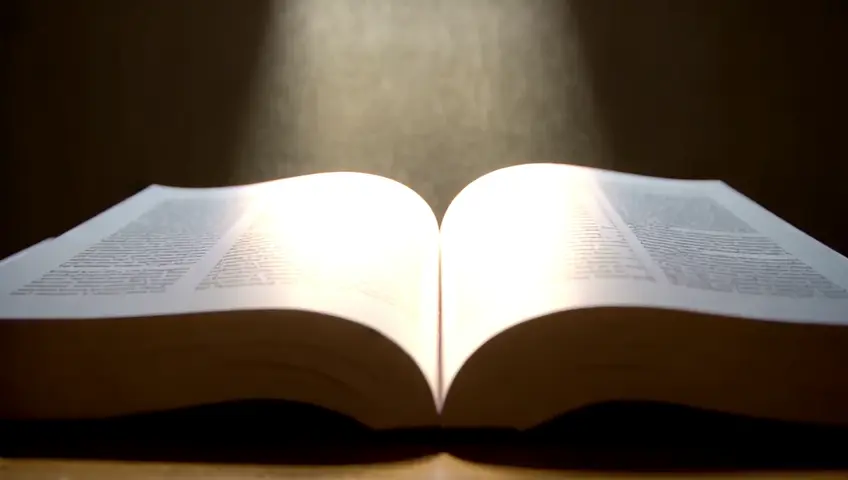 create the image An open Bible with a beam of light illuminating it.
