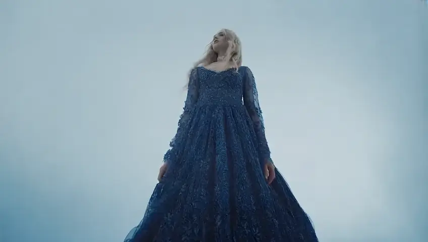 young woman with long blond hair wearing highly embroidered dark blue dress with lace choker, from below, steps into the air. Walking on air into the clouds.