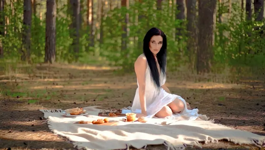 A beautiful woman around 40 years old sits across from me, She has fine, long black hair and green eyes. Her skin is somewhat pale. We are sharing a moment in a clearing in the midst of a dense forest. It is a nice afternoon for a picnic