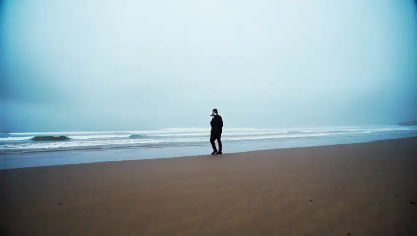 Homem andando na praia usando uma máscara de gás.