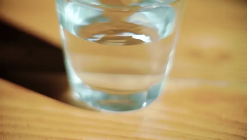 crie um video com imagens realista de um copo transparente com agua pela metade