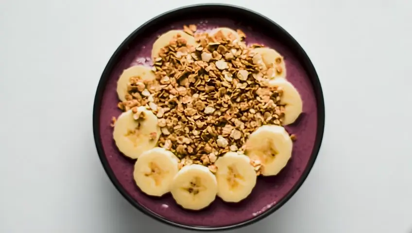 Câmera estática, uma tigela de açaí bem cremoso, coberta com granola e fatias de banana. De repente, o açaí começa a vibrar e a granula se move, formando manchas pretas. O *shift* acontece: a tigela se transforma em um Dálmata, com as manchas de granola virando suas marcas características. O vídeo termina com o cachorro balançando o rabo e lambendo a tigela vazia