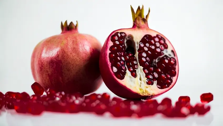 "A hyper-realistic, ultra-high-definition Leica M11-quality photograph of a pomegranate, presented in an elegant arrangement. The image features three perspectives: A whole pomegranate with flawlessly smooth, ruby-red skin and a crown-like calyx at the top, illuminated by soft, natural light that highlights its rich color, subtle textures, and organic imperfections. A freshly cut, halved pomegranate reveals the intricate, three-dimensional arrangement of jewel-like arils. The seeds glisten with a natural sheen, their translucent, ruby-red hues bursting with freshness, delicately encased by the thin, pale-yellow membrane. In the foreground, a small pile of loose arils, each reflecting light with a glass-like, juicy texture, adding to the realism. The background is pure white with soft, natural shadows that enhance depth and dimension, creating an ultra-lifelike representation. Every microscopic detail—from the delicate veins in the fruit’s membrane to the soft, matte finish of the skin—is captured with extreme precision, evoking the masterful quality of professional Leica photography."[Pedestal down,Tilt up][Truck left,Pan right,Tracking shot]