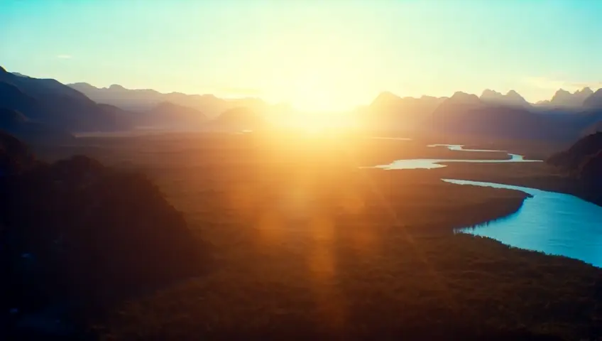 Create a serene video of a golden light shining in the sky, spreading across mountains, rivers, forests, and people of different cultures holding hands. The light symbolizes unity and connection. The camera should slowly pan from the sky to the earth, highlighting the interconnectedness of all life. Use soft, spiritual background light effects and warm tones