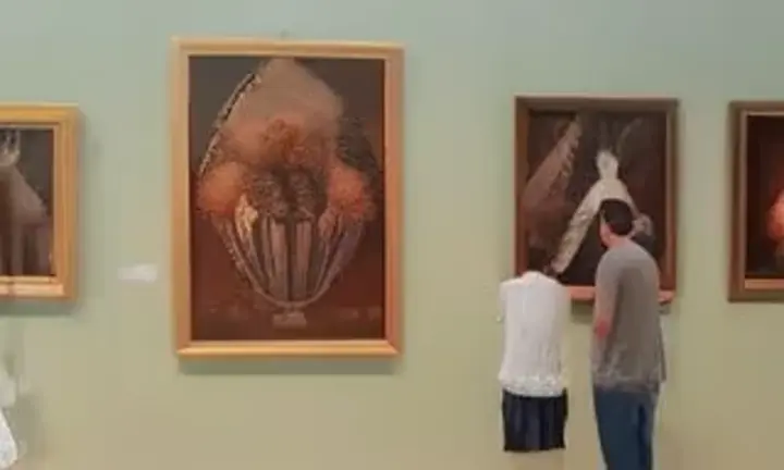 two men looking at paintings in a museum