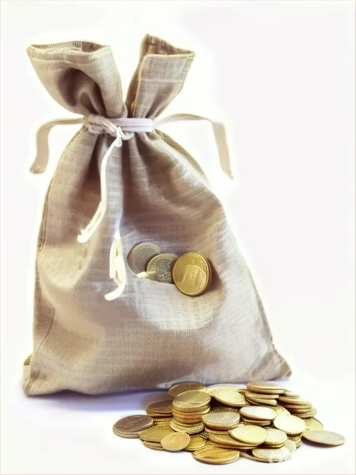 A bag of money with holes placed on top of a pile of coins.