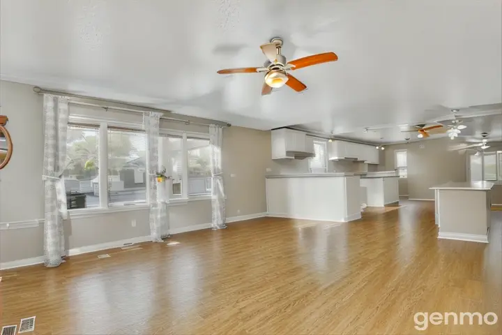 an empty living room with wood floors and a ceiling fan