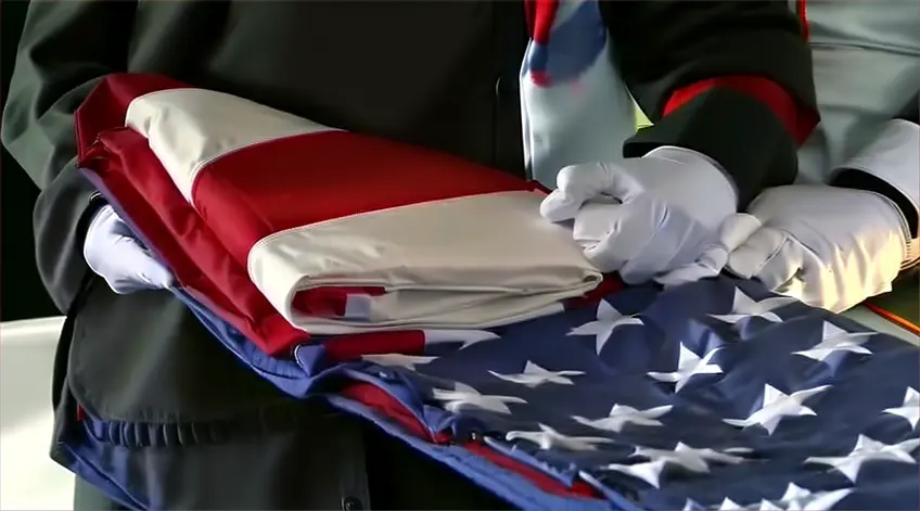 a man in a uniform wearing white gloves holding an American flag