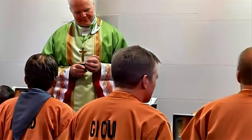 a catholic priest standing in front of a group of inmates in a prison