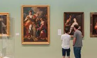 two men looking at paintings in a museum