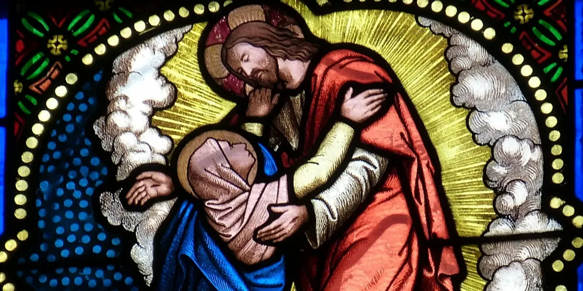 a stained glass window of a man holding a baby