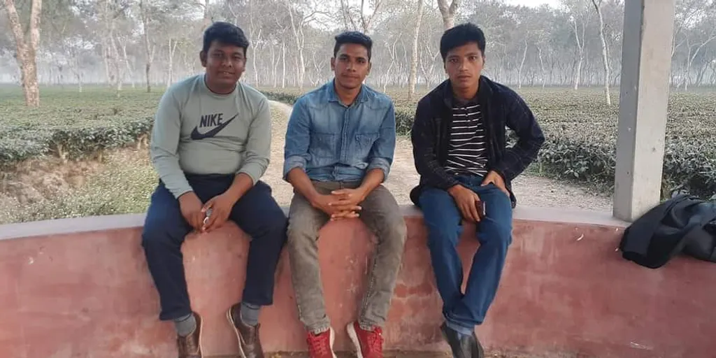 three men are sitting on a wall outside