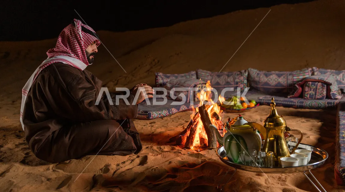 a man sitting next to a campfire in the desert