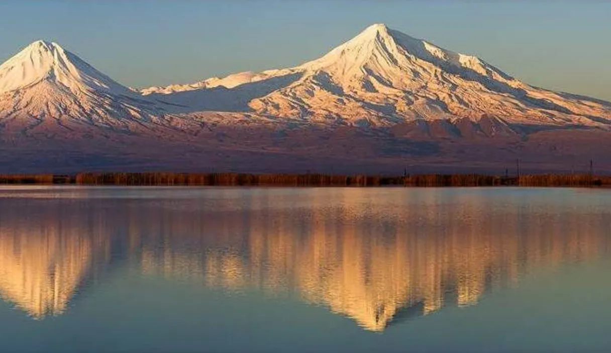 a snow covered mountain is reflected in a lake