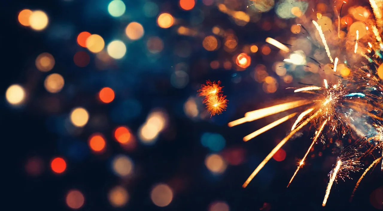 a close up of a fireworks with blurry lights in the background