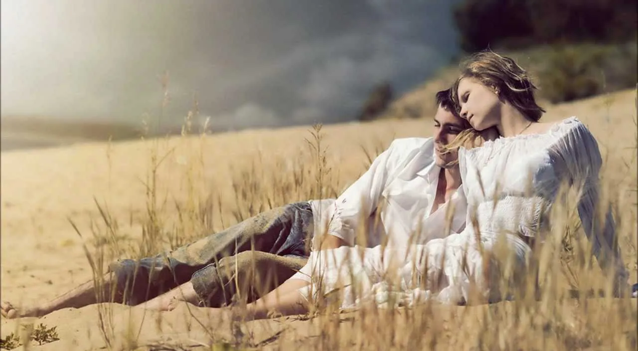 a man and a woman sitting in a field