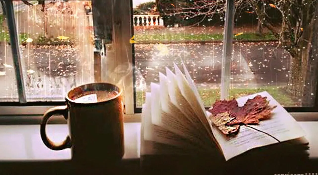 A minimalistic shot of a cup of coffee and a book on a window sill overlooking a concrete cityscape