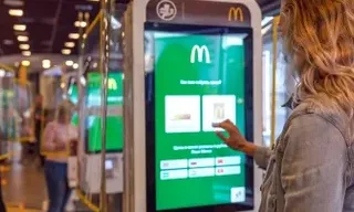 a woman standing in front of a machine to order food from mcdonalds