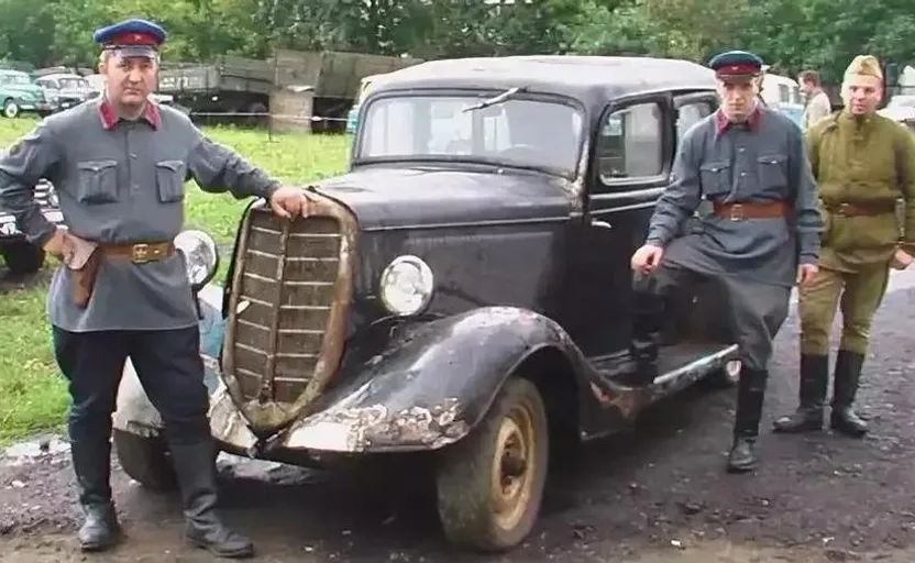 a group of men standing next to an old car