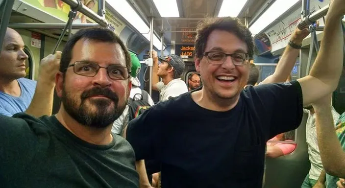 a couple of men standing on a train next to each other