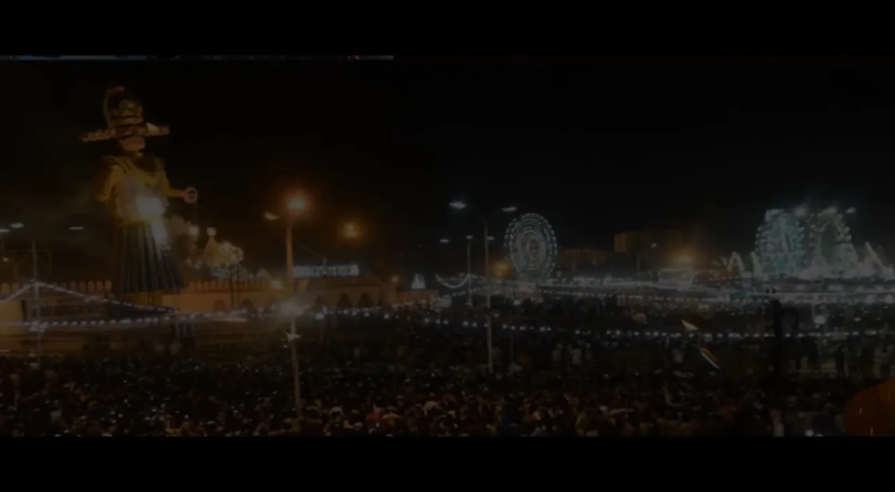 a crowd of people standing around a carnival at night