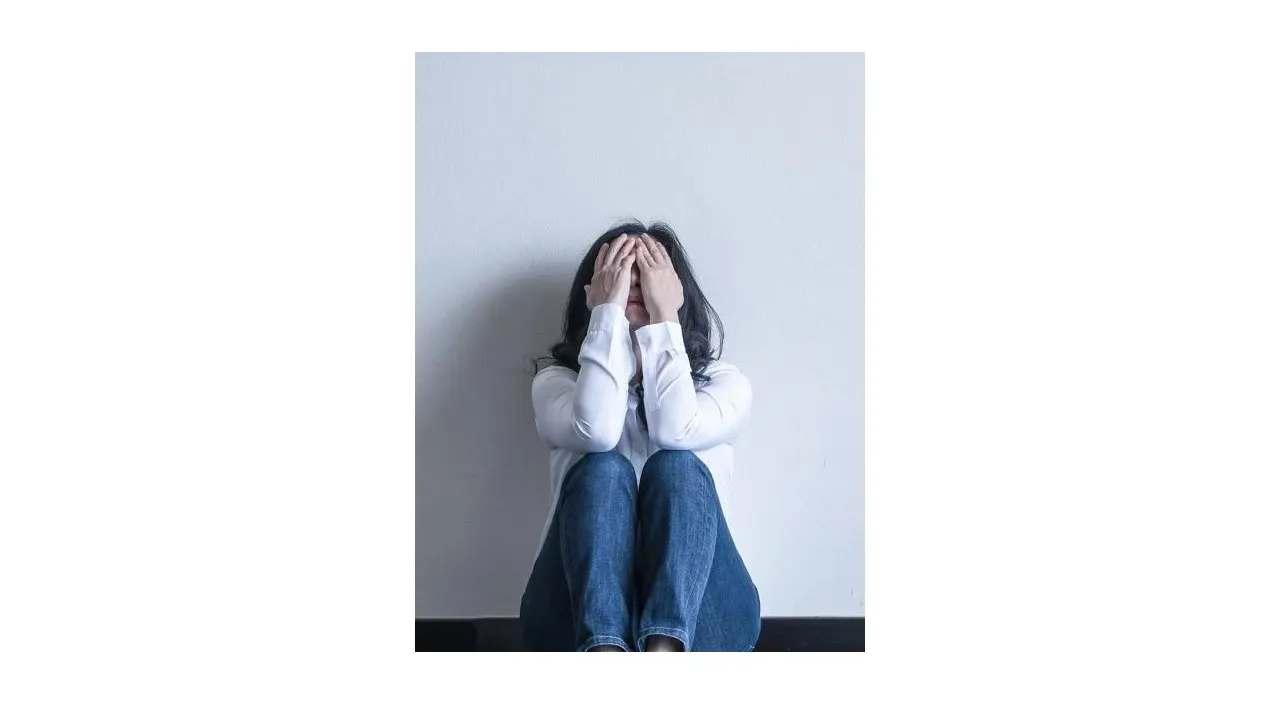 a woman sitting on the floor covering her face with her hands