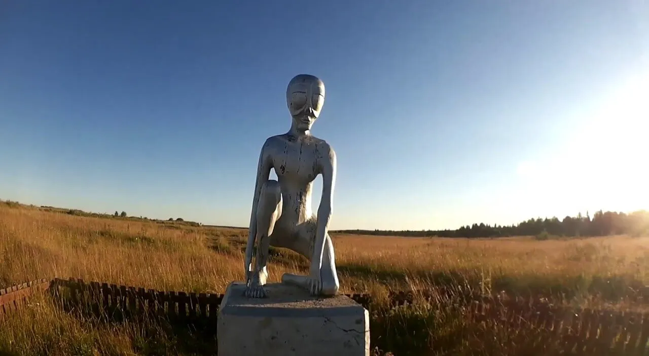 a statue of a alien sitting in a field