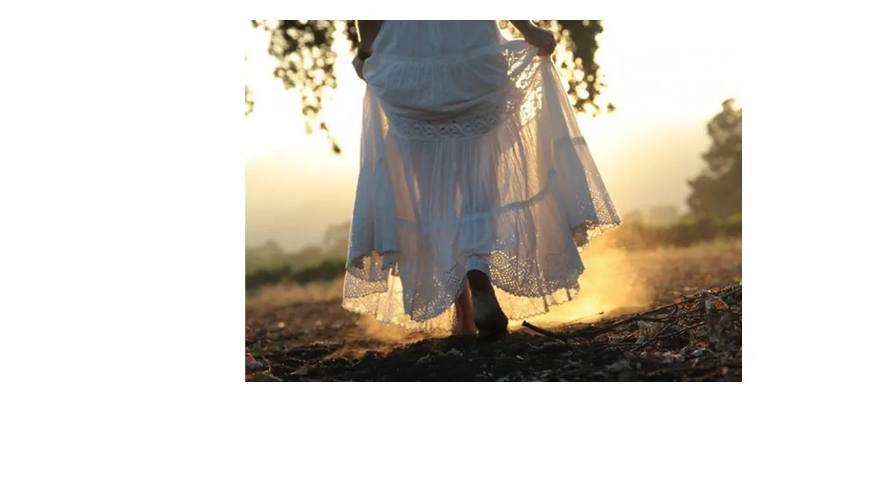 a woman in a white dress standing in a field