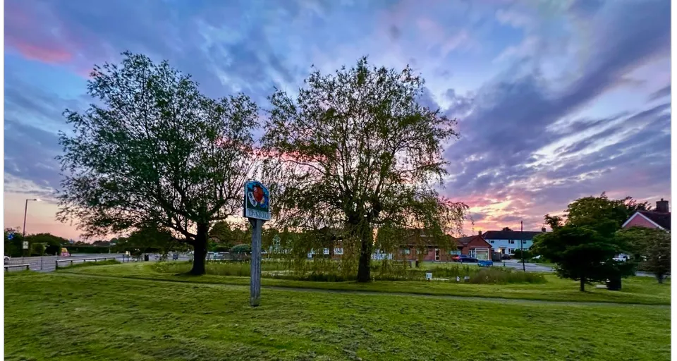 a grassy field with trees and a street sign