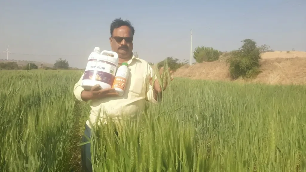 a man standing in a field holding a bottle of milk