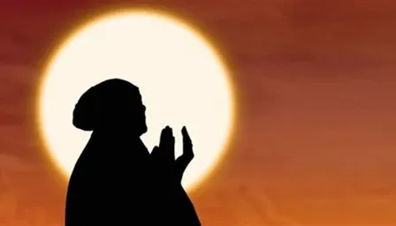 a silhouette of a person praying in front of the sun