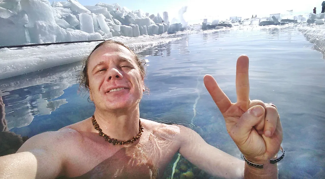 a man in a body of water making a peace sign