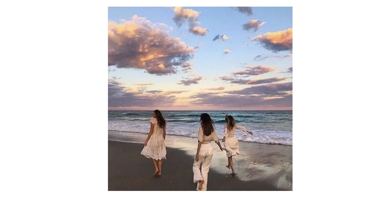 three women walking on the beach at sunset