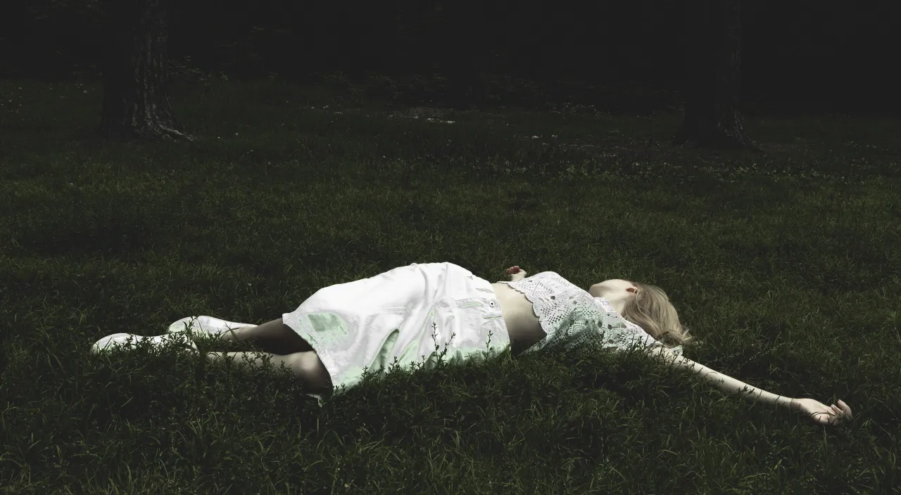 a woman laying in the grass in a white dress