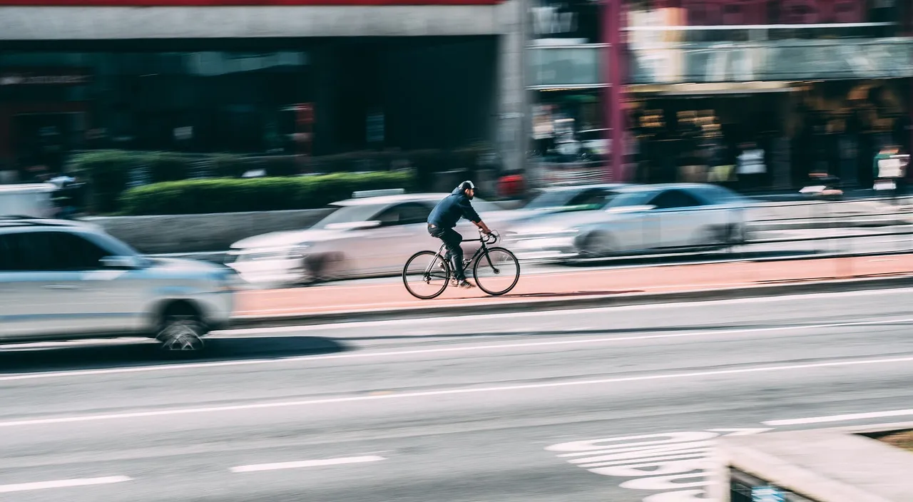 a man riding a bike down a street next to parked cars