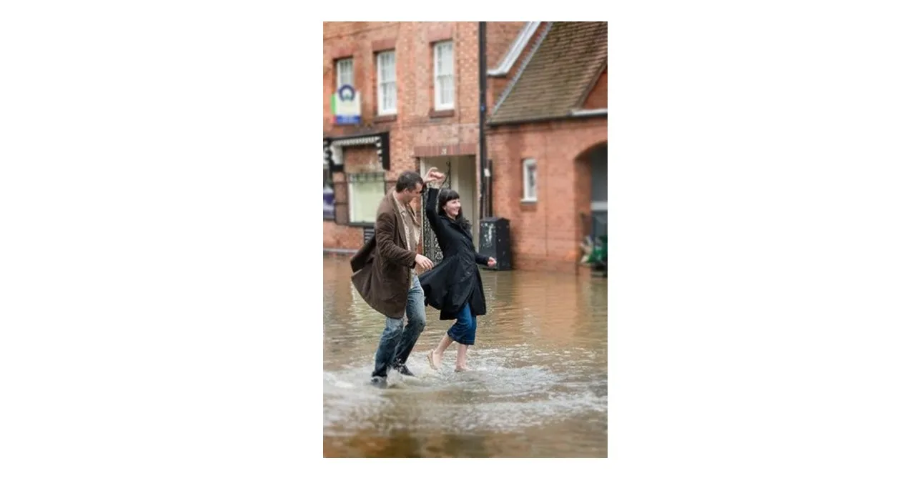 a couple of people walking through a flooded street