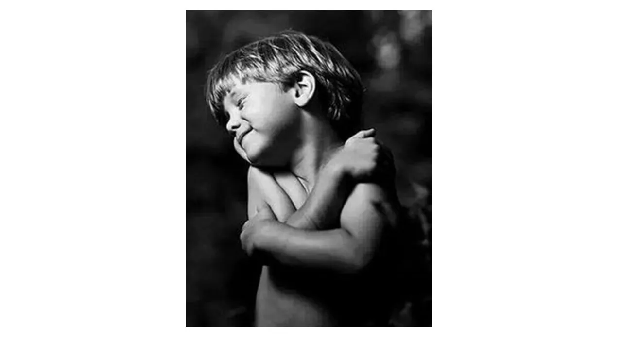 a black and white photo of a young boy hug yorself