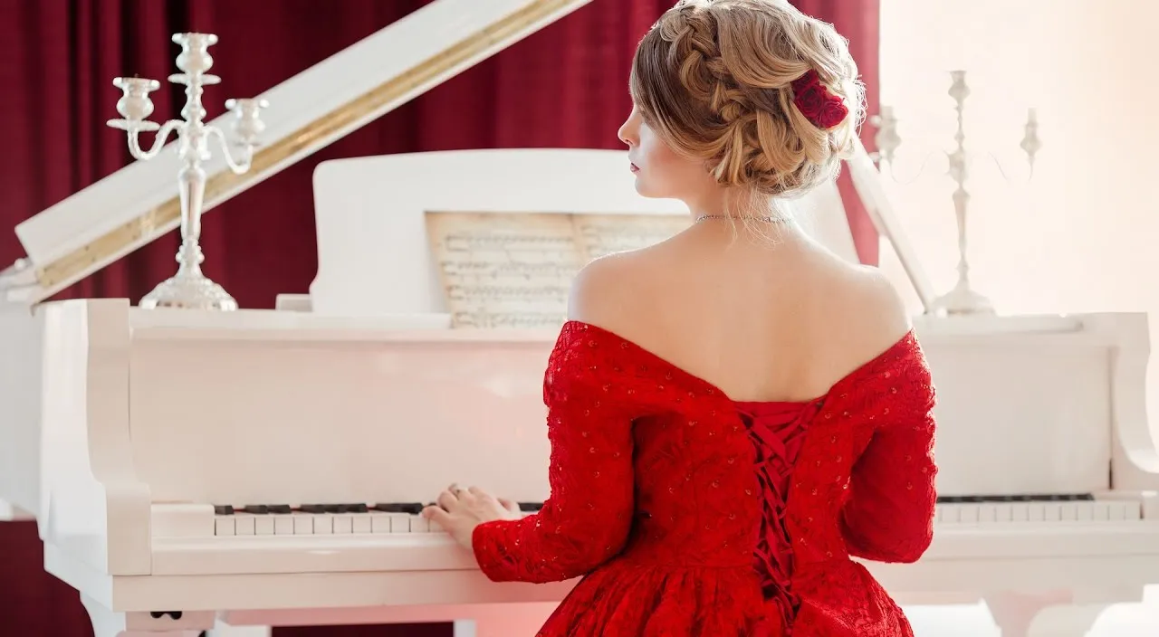 a woman in a red dress playing a white piano