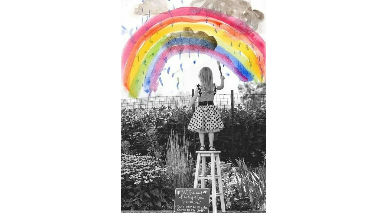 a woman standing on top of a ladder under a rainbow colored umbrella