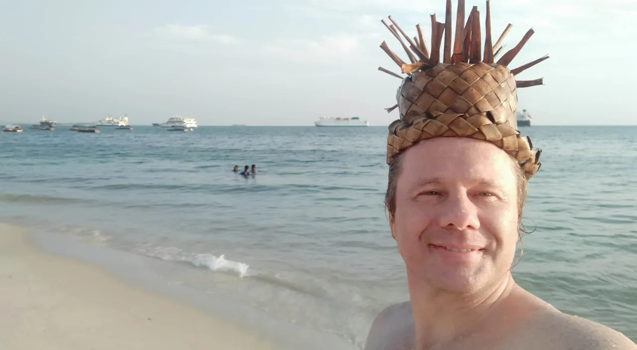 a man wearing a pineapple hat on the beach