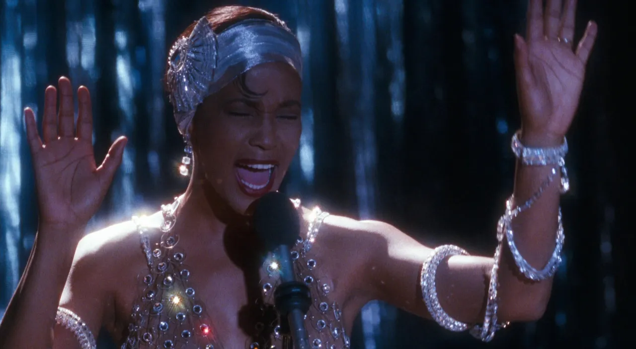 a woman in a silver dress singing into a microphone