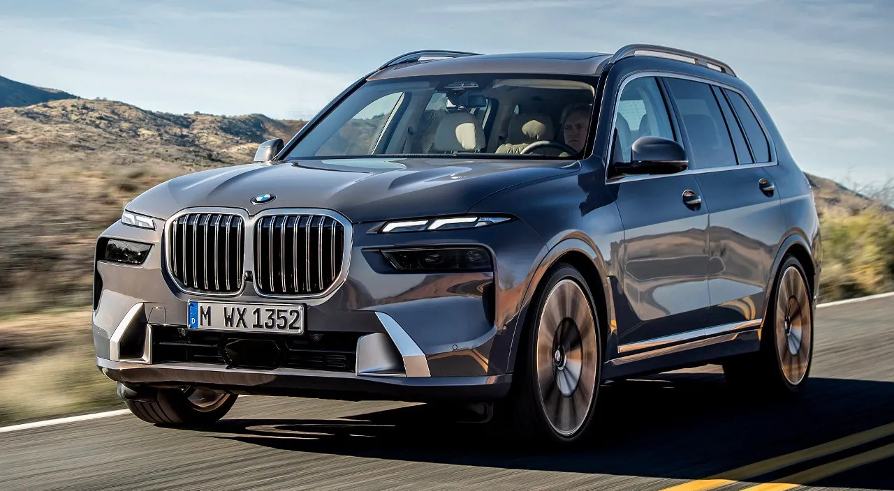 a silver bmw x7 driving down a road