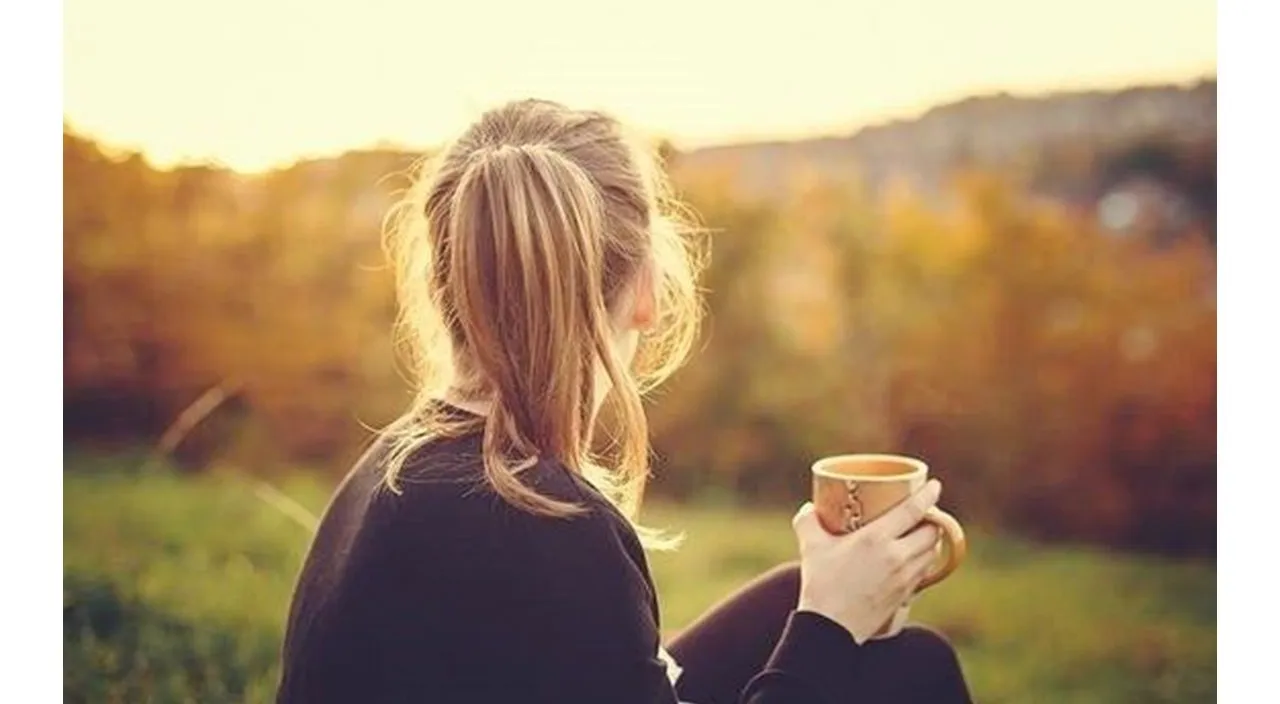 a woman sitting on a bench holding a cup of coffee