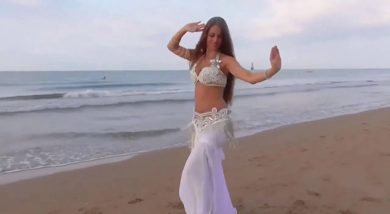 a woman standing on top of a beach next to the ocean